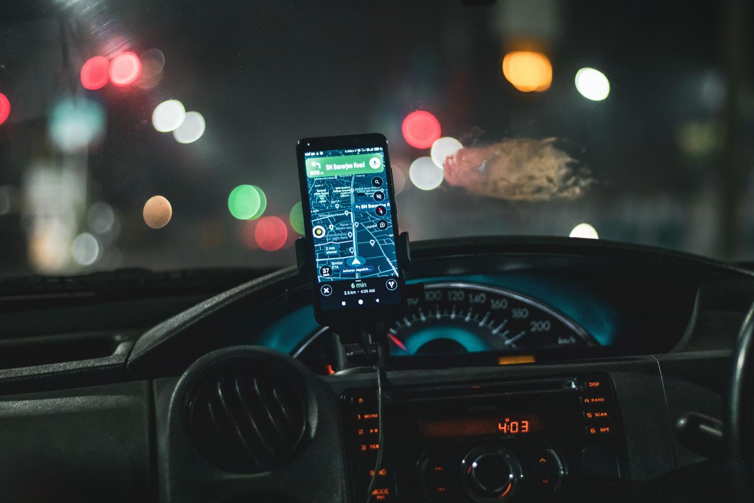 Smartphone con navegación GPS montado en el salpicadero de un coche por la noche