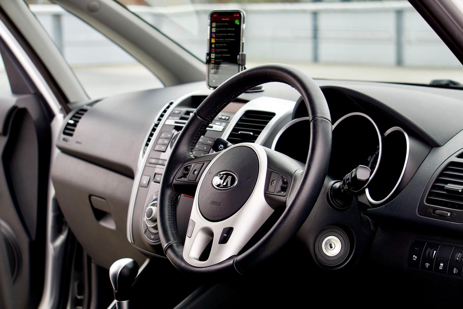 Primer plano de un interior de coche moderno con soporte para smartphone y volante