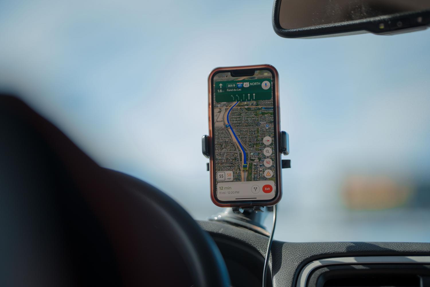 Uso moderno del GPS mediante un smartphone montado en el salpicadero de un coche, ilustrando la navegación civil actual.