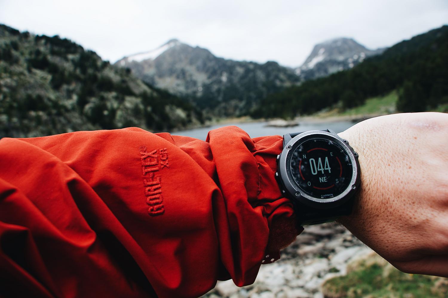Sender revisando su reloj deportivo con GPS en un paisaje montañoso para navegación outdoor