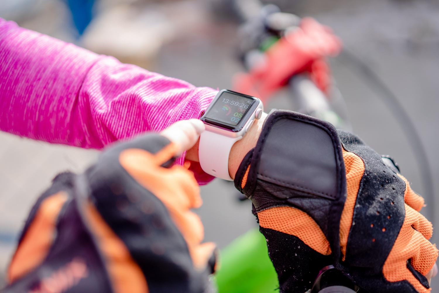 Ciclista consultando las métricas de rendimiento en su reloj deportivo durante una ruta