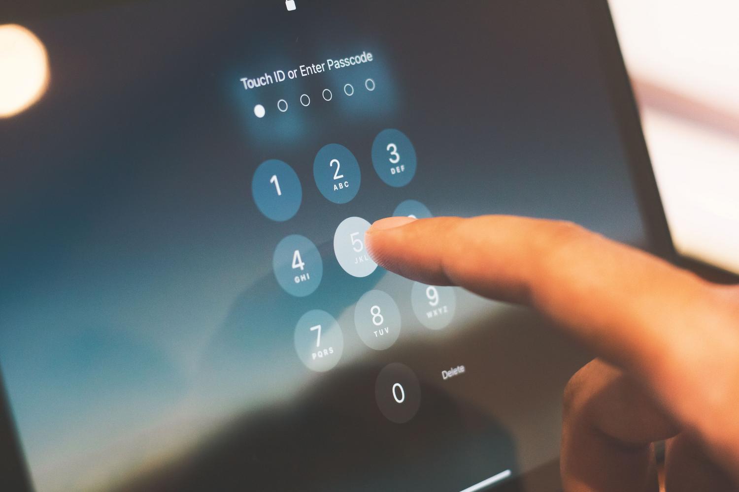 Primer plano de un dedo introduciendo el código de acceso en la pantalla de seguridad de un smartphone.