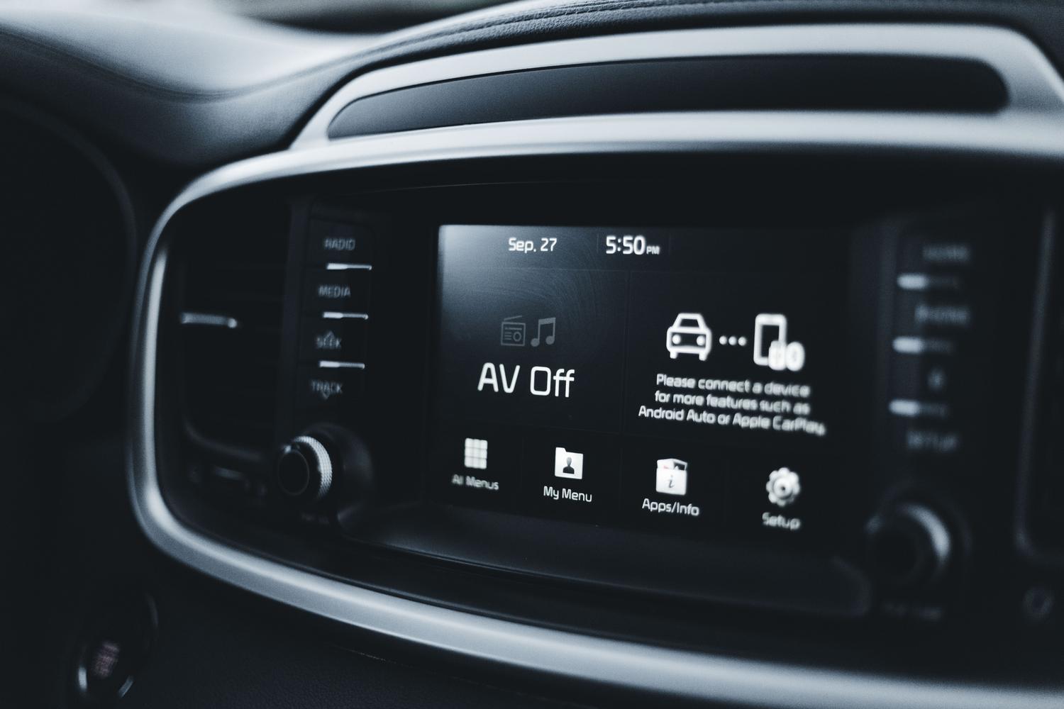 Primer plano de la pantalla de un salpicadero de coche moderno que muestra diversas opciones tecnológicas y de conectividad.