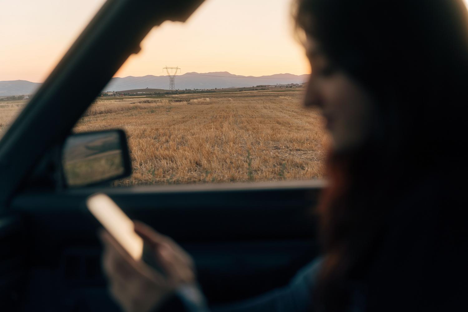 Mujer utilizando el smartphone dentro de un vehículo, representando la comodidad de llevar la documentación en el móvil