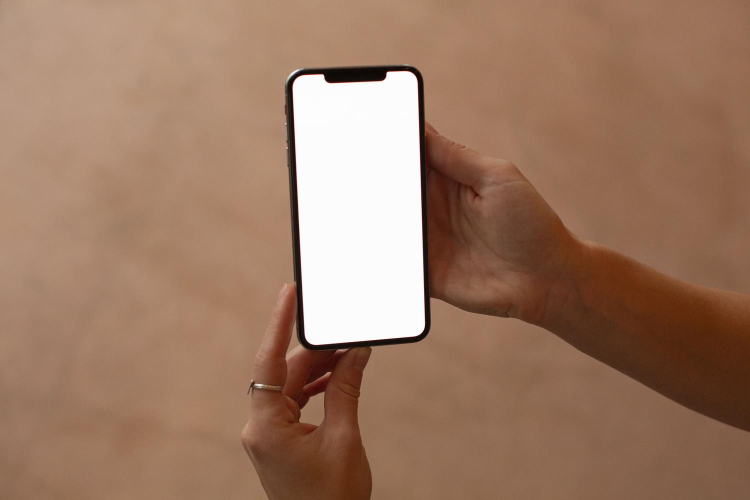 Primer plano de manos sosteniendo un smartphone con pantalla en blanco, ideal para ilustrar la conceptualización de la cartera digital de tráfico