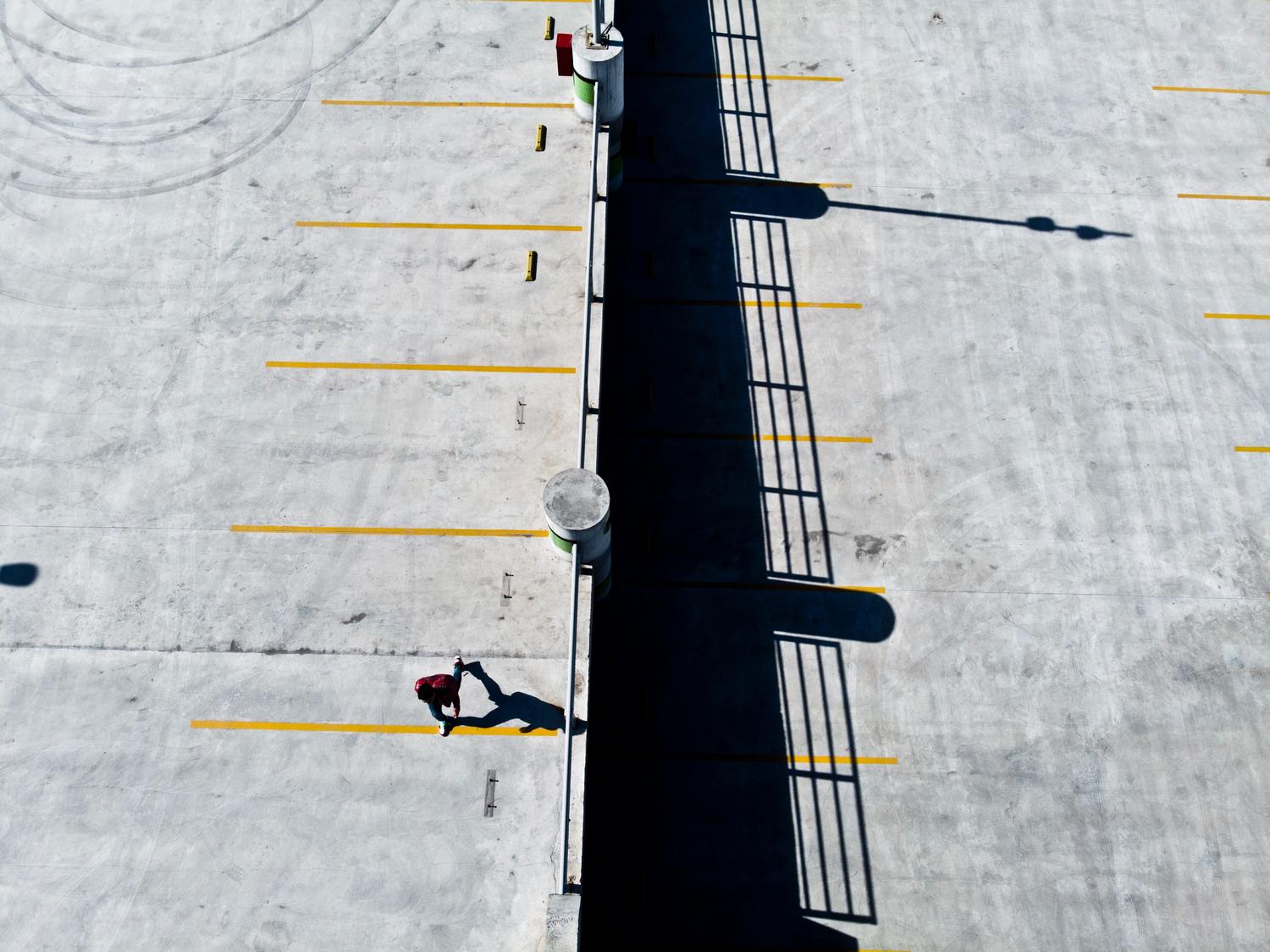 Persona caminando por un parking vacío, representando la sensación de desorientación al buscar el coche.