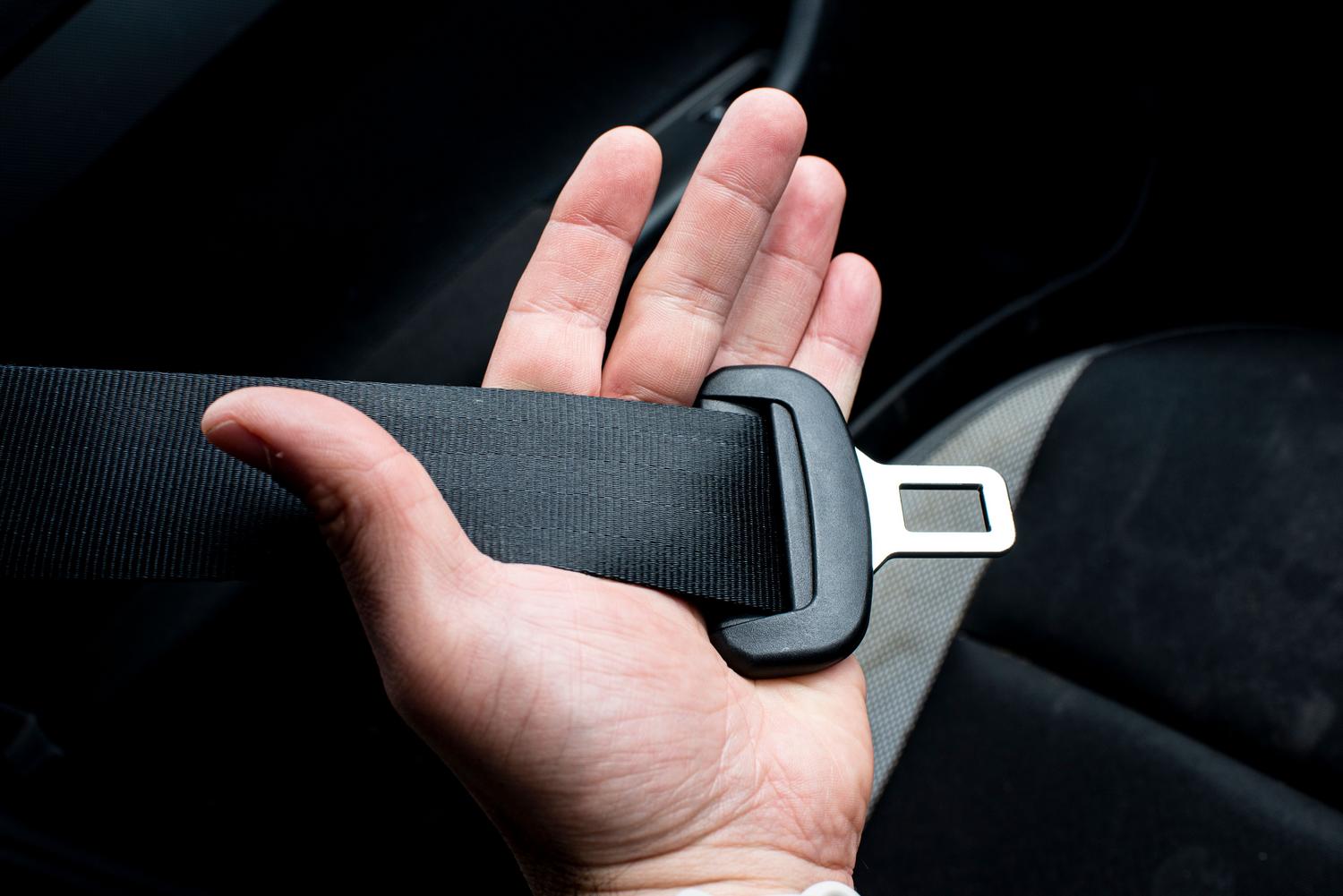 Mano sujetando el cinturón de seguridad de un coche, elemento fundamental de la seguridad pasiva para proteger a los ocupantes.