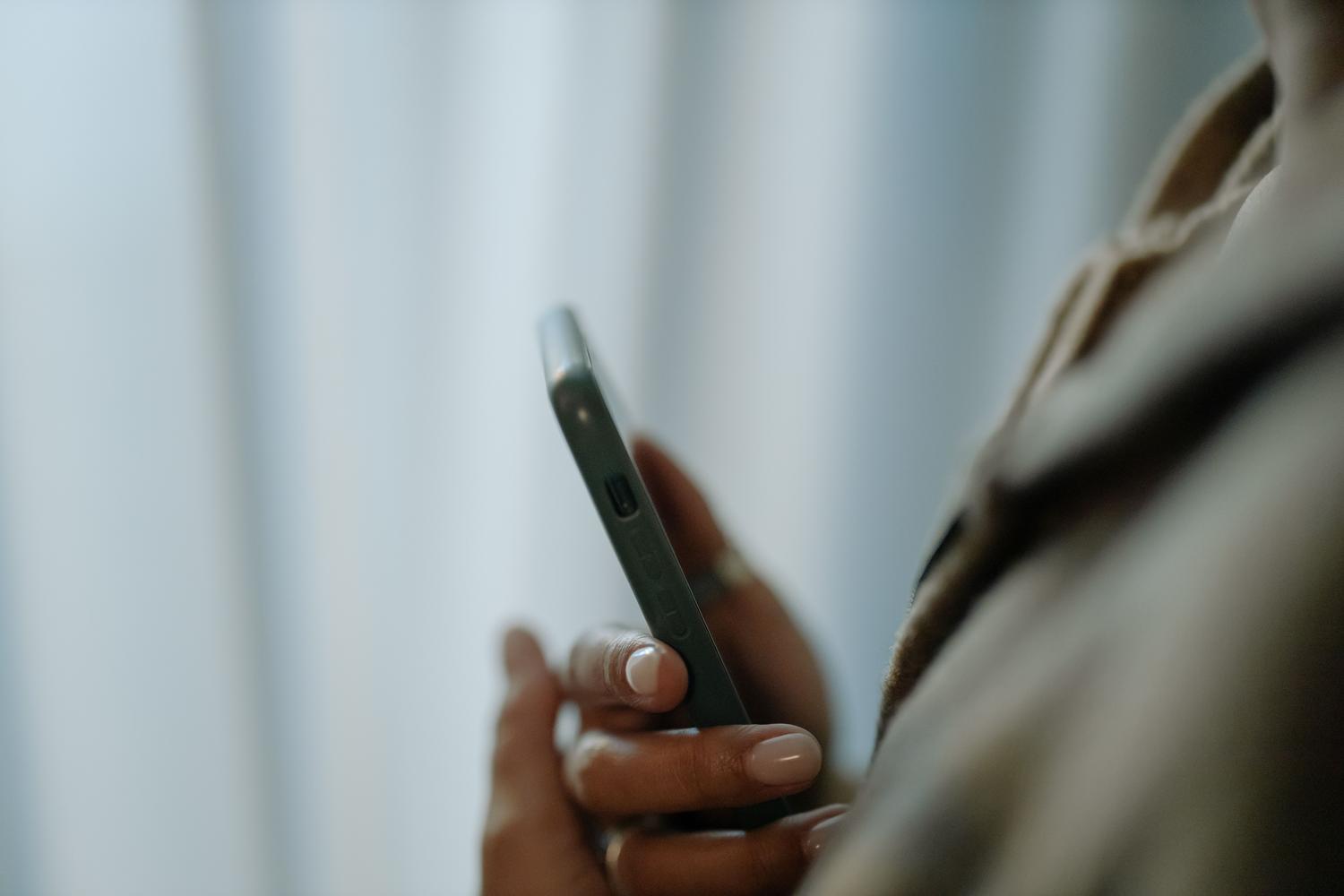 Primer plano de una mano sosteniendo un smartphone en un entorno limpio y neutro, transmitiendo una sensación de privacidad y anonimato.
