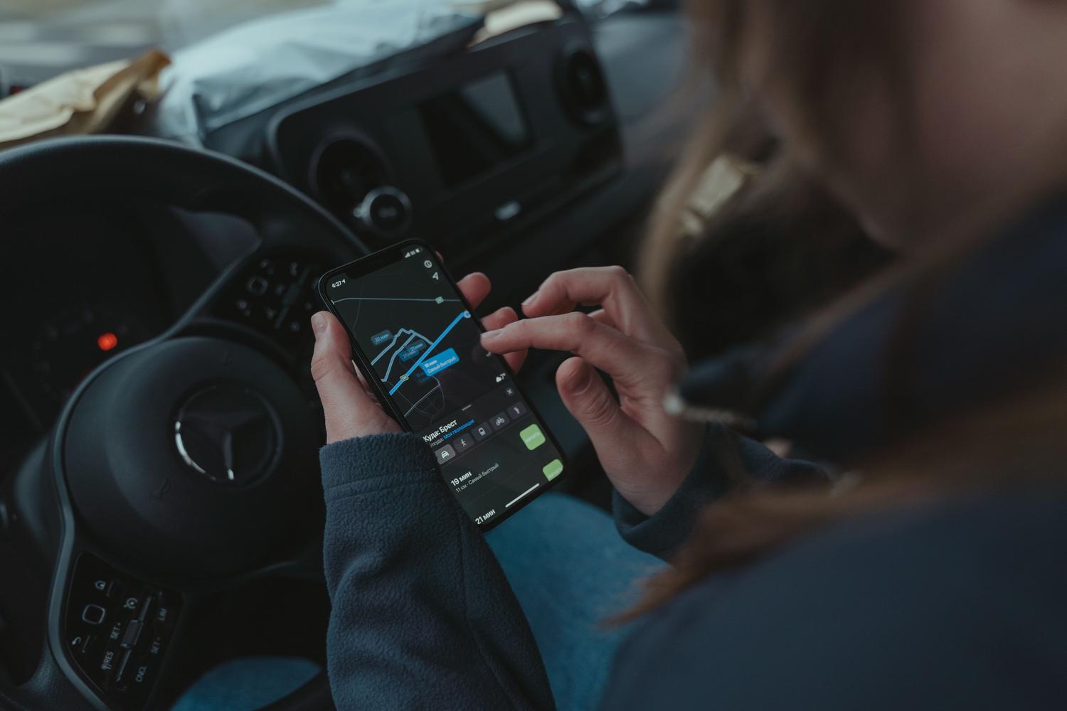 Persona utilizando una aplicación de navegación conversacional asistida por IA en un smartphone dentro del coche