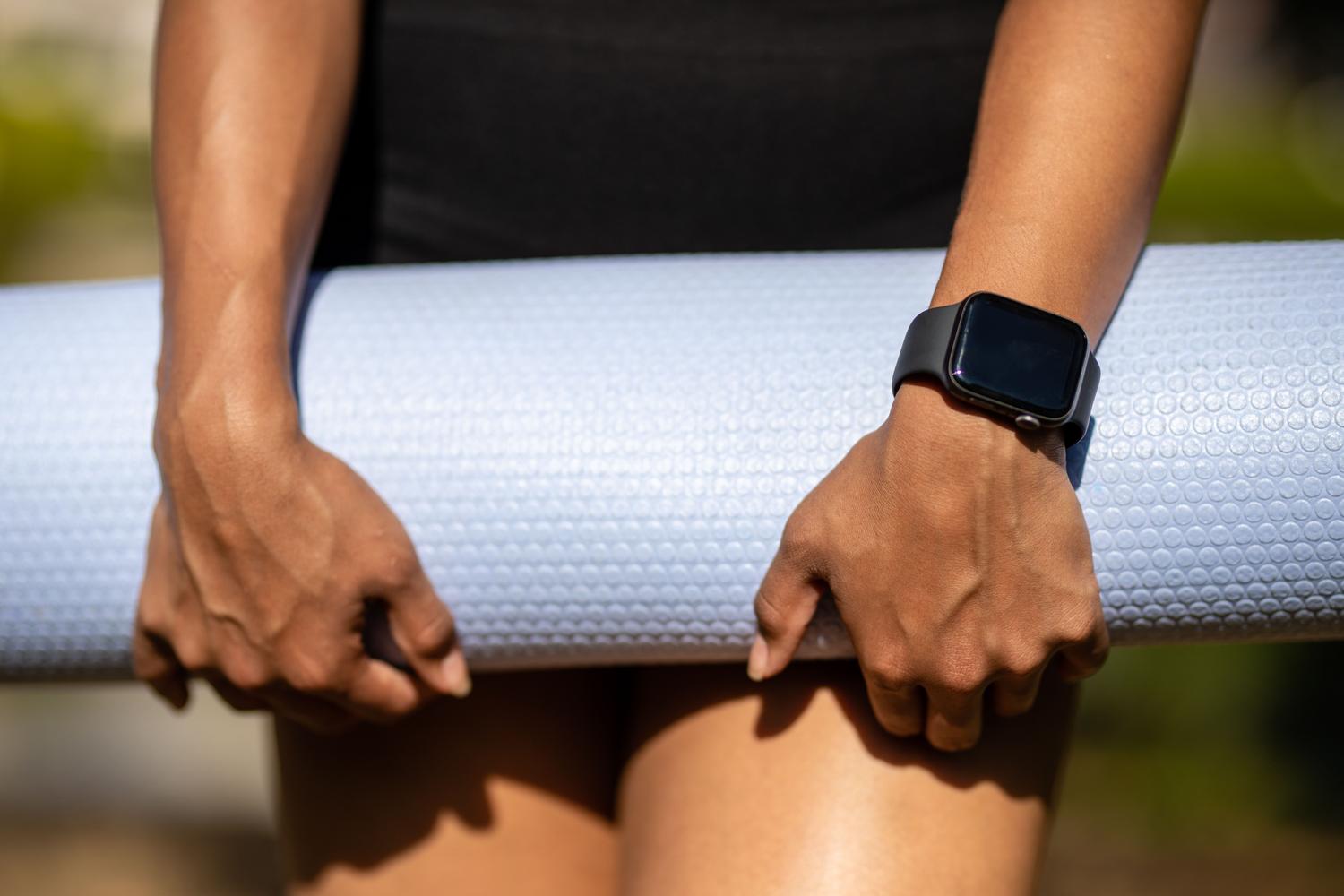 Persona con un smartwatch y una esterilla de yoga, representando los perfiles de bienestar y salud.