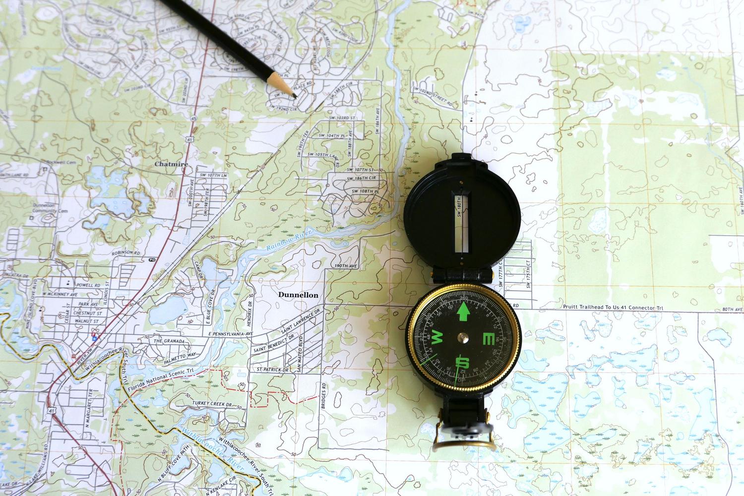 Primer plano de un mapa topográfico detallado con una brújula y un lápiz para trazar rutas.