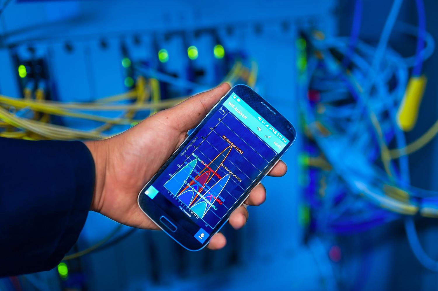Profesional de IT monitoreando la infraestructura de red con un smartphone Android para detectar anomalías y evitar interceptaciones de datos.