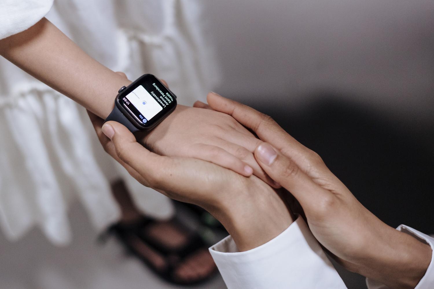 Primer plano de una mano adulta protegiendo la de un niño que usa un wearable, enfatizando la seguridad y el cuidado.