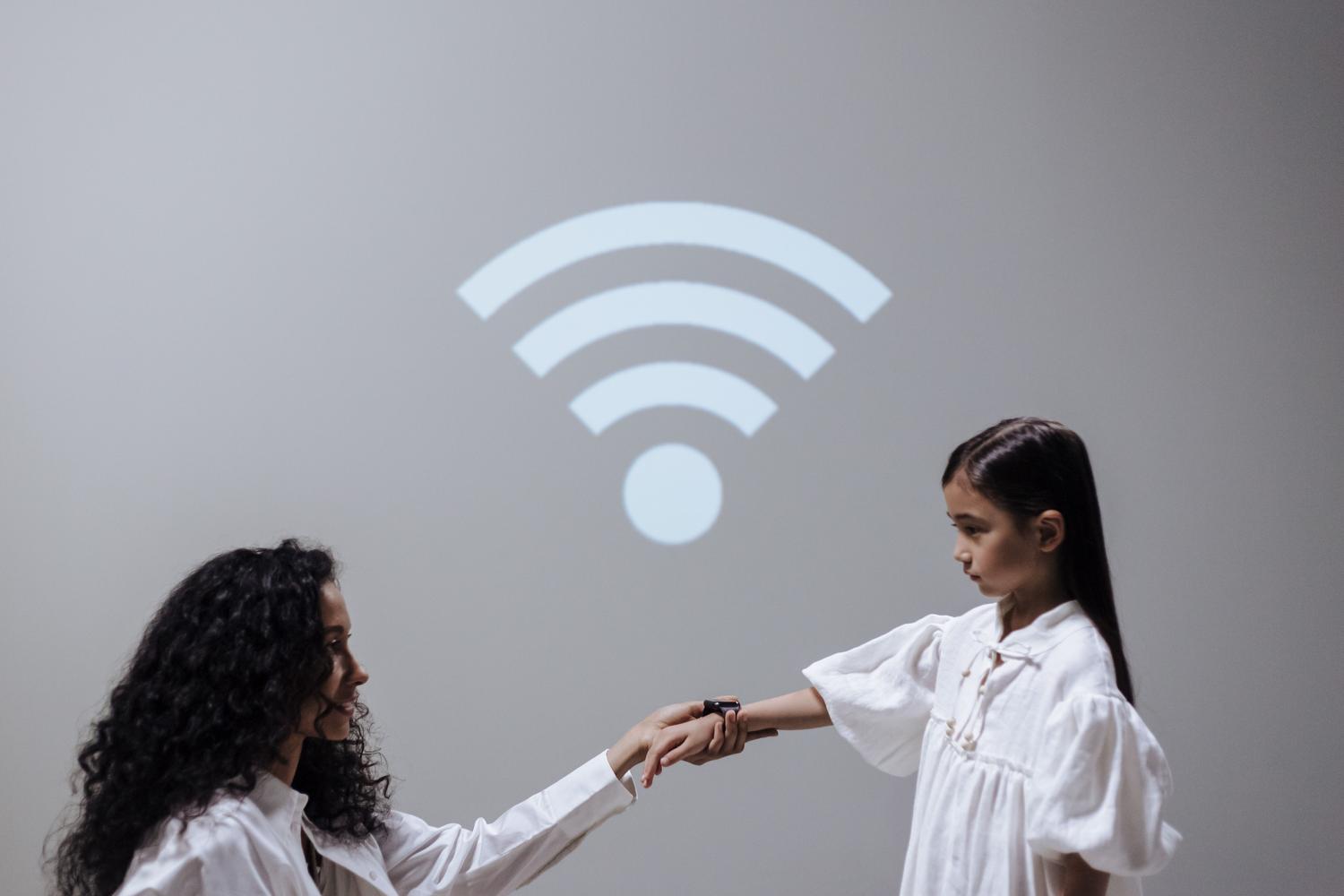 Concepto de conectividad inalámbrica con madre e hija y un símbolo de Wi-Fi, representando la comunicación constante de los wearables.